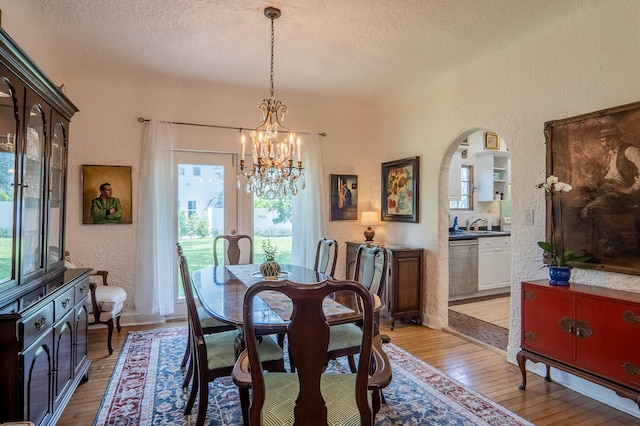 dining room featuring an inviting chandelier, a textured ceiling, a textured wall, and plenty of natural light
