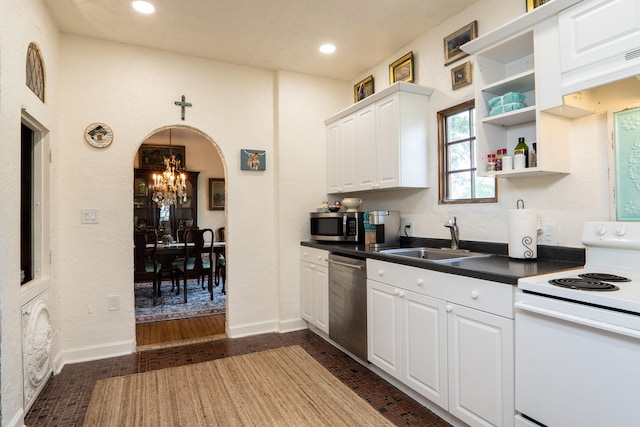 kitchen with dark countertops, brick floor, a chandelier, a sink, and appliances with stainless steel finishes