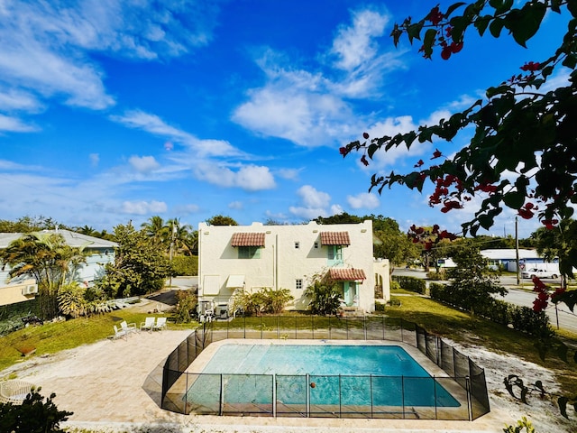 back of property with a fenced in pool, stucco siding, and fence