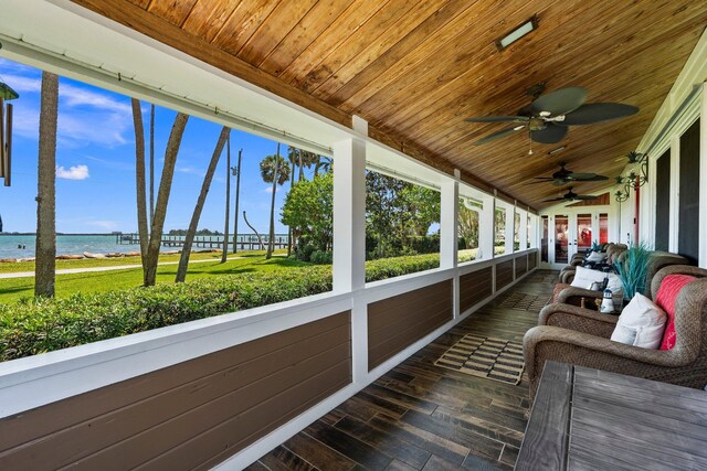 sunroom with a ceiling fan and a water view