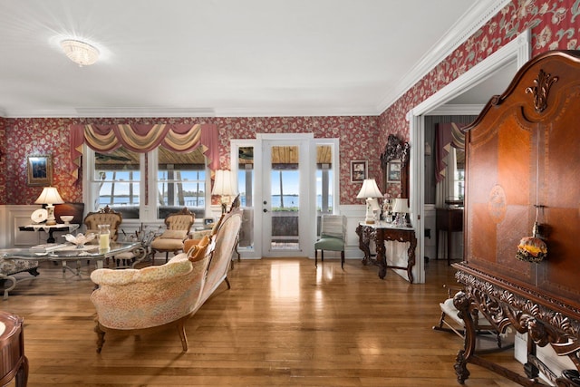 living area with wallpapered walls, a wainscoted wall, and crown molding