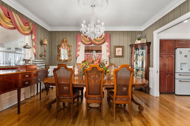 dining space with a chandelier, wallpapered walls, light wood finished floors, and ornamental molding