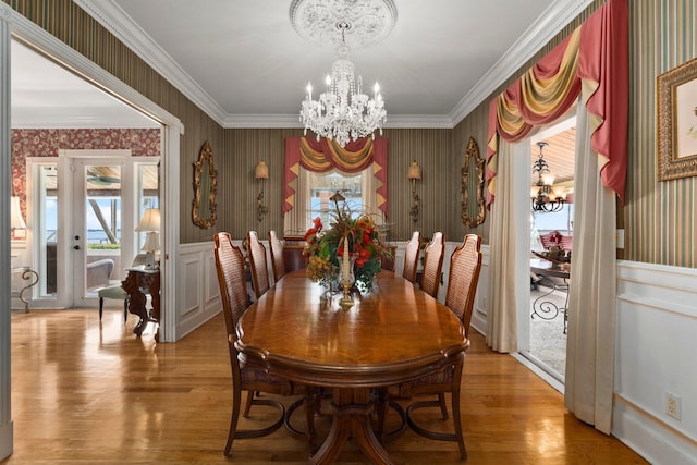 dining room with an inviting chandelier, crown molding, wallpapered walls, and light wood-type flooring