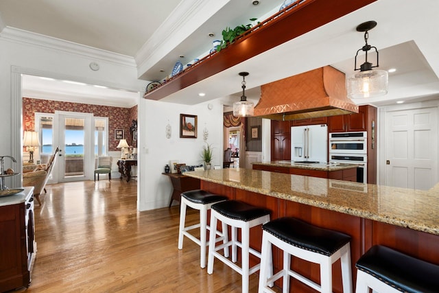 kitchen with pendant lighting, white appliances, light wood-style floors, and crown molding