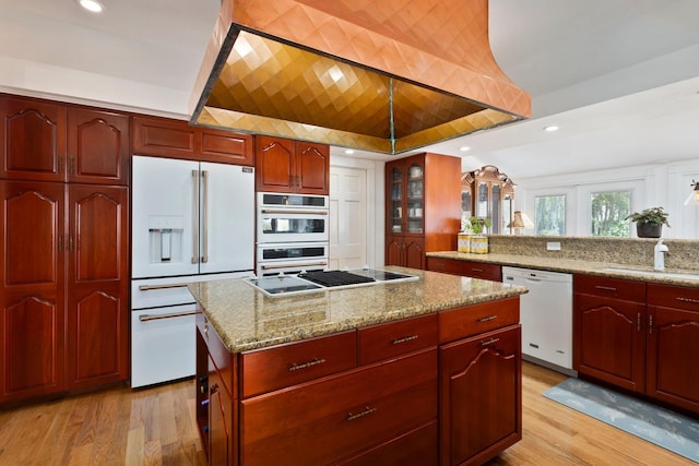 kitchen featuring a sink, white appliances, light wood-type flooring, reddish brown cabinets, and light stone countertops