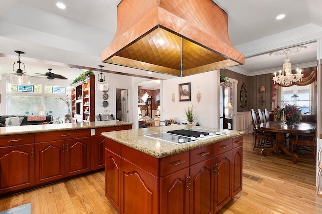 kitchen featuring light wood finished floors, a center island, hanging light fixtures, open floor plan, and ceiling fan with notable chandelier