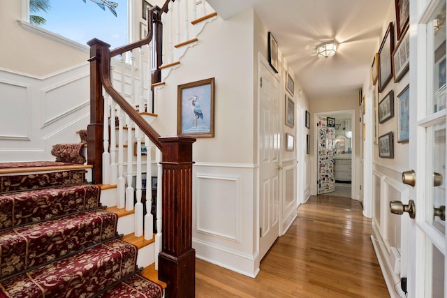 interior space featuring wood finished floors, a decorative wall, and wainscoting