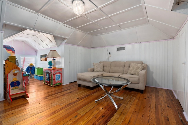 living room featuring hardwood / wood-style flooring, wooden walls, vaulted ceiling, and visible vents