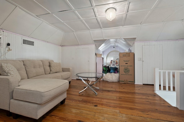 living area with hardwood / wood-style flooring, wooden walls, lofted ceiling, and visible vents