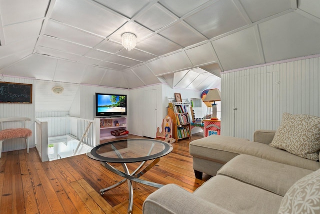 living area with lofted ceiling, hardwood / wood-style flooring, and wooden walls
