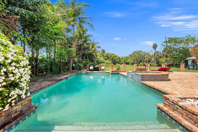 view of pool featuring fence, a patio area, and a pool with connected hot tub