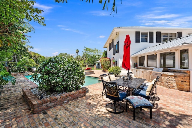 view of patio with an outdoor kitchen, an outdoor pool, outdoor dining area, and a grill