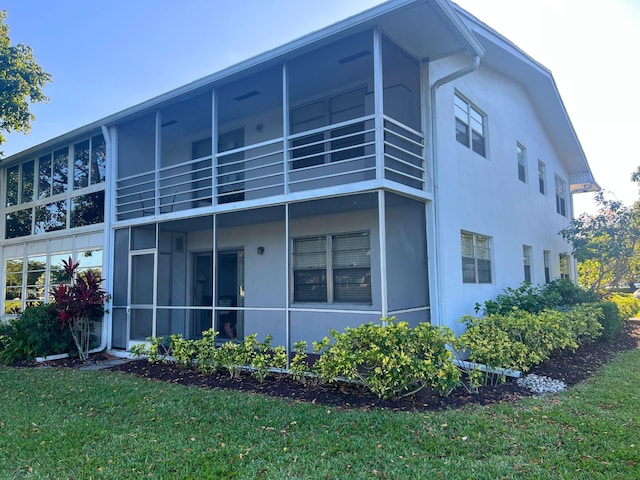exterior space with stucco siding and a lawn