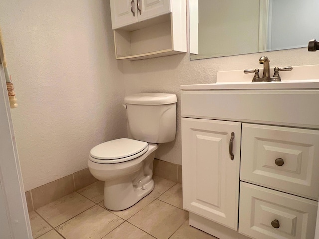 bathroom featuring toilet, tile patterned flooring, vanity, and baseboards