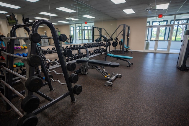 exercise room featuring baseboards, plenty of natural light, and a paneled ceiling