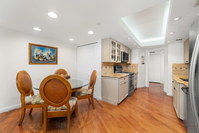 4301 N Ocean Blvd Unit 203, Boca Raton, FL 33431 - kitchen featuring decorative backsplash, light wood-type flooring, glass insert cabinets, stainless steel appliances, and visible vents