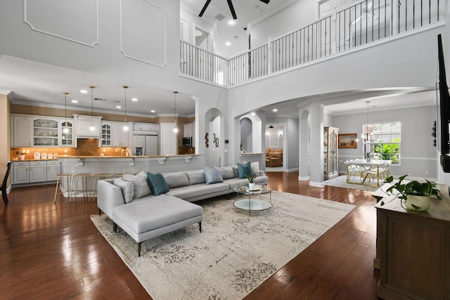 869 SW Habitat Ln, Palm City, FL 34990 - living area featuring arched walkways, a ceiling fan, crown molding, dark wood-type flooring, and a high ceiling
