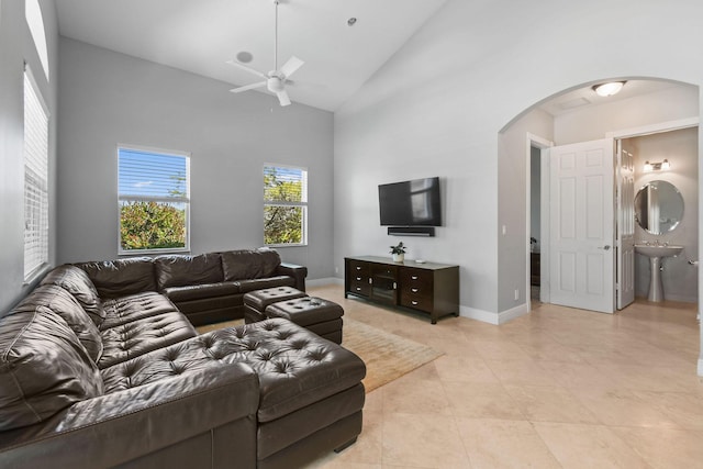869 SW Habitat Ln, Palm City, FL 34990 - living room with arched walkways, ceiling fan, high vaulted ceiling, light tile patterned floors, and baseboards