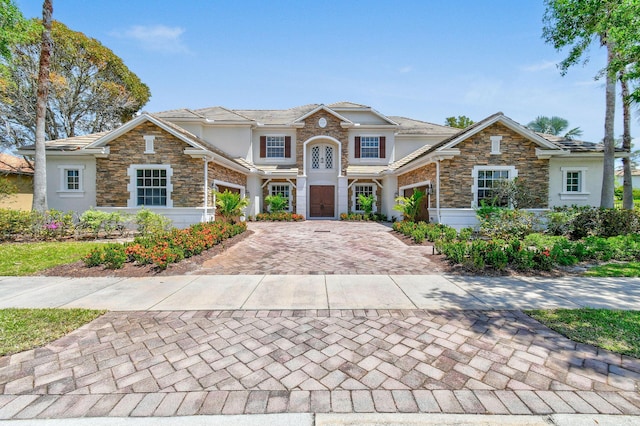 869 SW Habitat Ln, Palm City, FL 34990 - view of front of house with a garage, stone siding, and decorative driveway