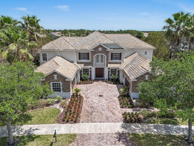 869 SW Habitat Ln, Palm City, FL 34990 - traditional home featuring stone siding, decorative driveway, stucco siding, and an attached garage