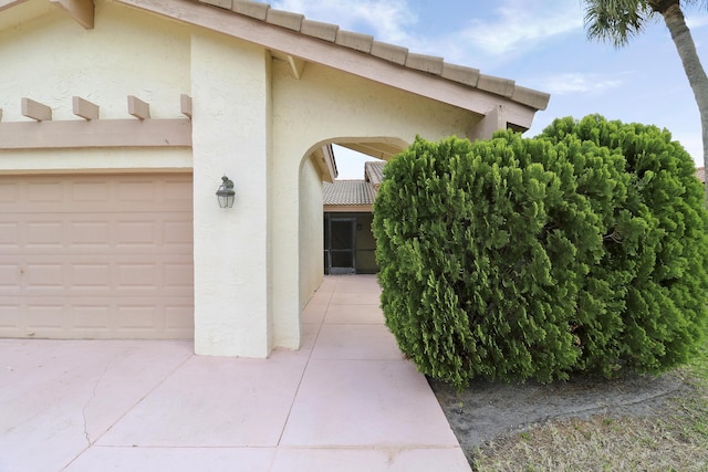 doorway to property featuring stucco siding and a garage