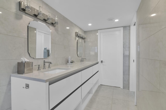 full bath featuring tile walls, a sink, tile patterned flooring, and double vanity