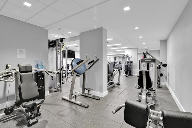 exercise room with baseboards, a paneled ceiling, and recessed lighting