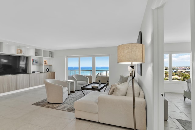 living area with a wealth of natural light, light tile patterned flooring, and a water view