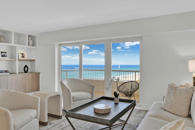 living area with light wood-style flooring, baseboards, and a water view