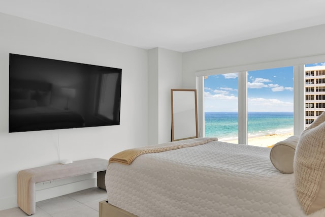 bedroom with a beach view, a water view, multiple windows, and light tile patterned floors