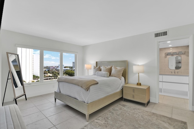 bedroom featuring baseboards, visible vents, connected bathroom, and light tile patterned floors