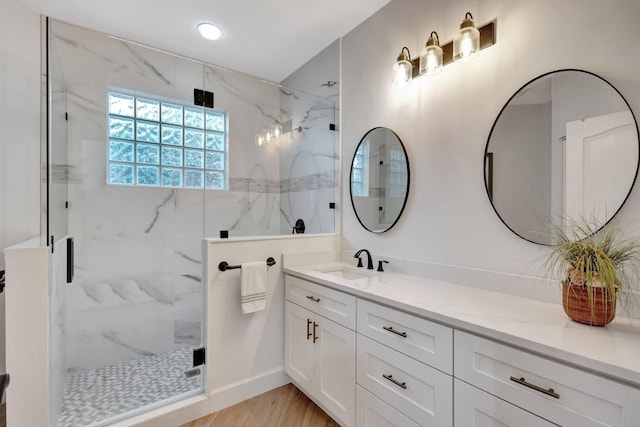 full bath with wood finished floors, vanity, and a marble finish shower