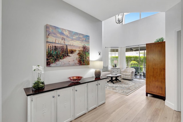 interior space featuring light wood-style flooring, a high ceiling, and a wealth of natural light
