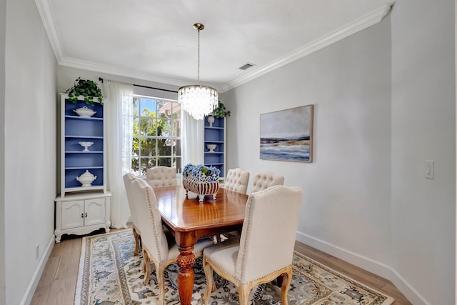 dining space featuring crown molding, light wood-style floors, baseboards, a notable chandelier, and visible vents