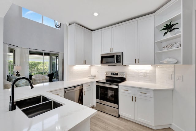 kitchen featuring open shelves, plenty of natural light, stainless steel appliances, and a sink