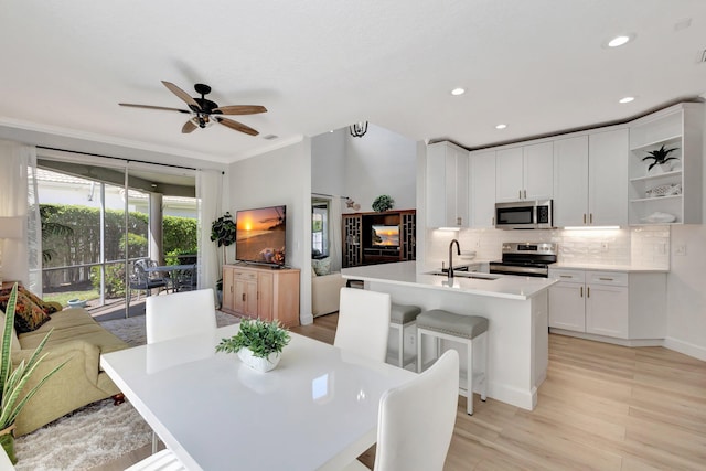 kitchen with a ceiling fan, a sink, stainless steel appliances, backsplash, and white cabinetry