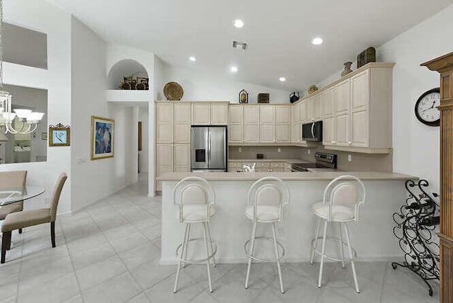 kitchen featuring stainless steel appliances, a kitchen bar, visible vents, a peninsula, and light countertops