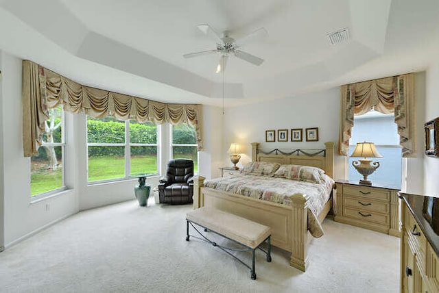 bedroom with visible vents, a ceiling fan, light colored carpet, and a raised ceiling