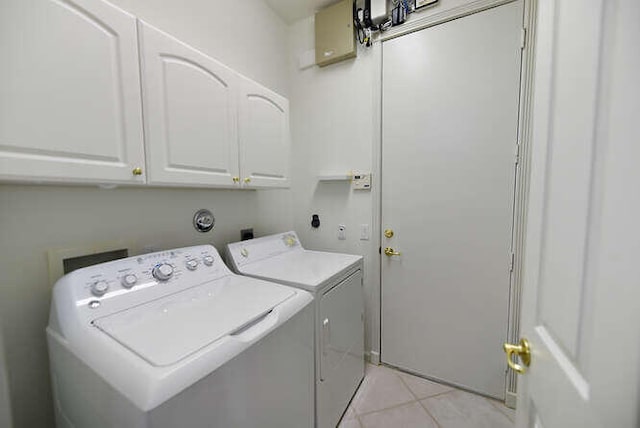 laundry room with light tile patterned flooring, cabinet space, and washing machine and clothes dryer