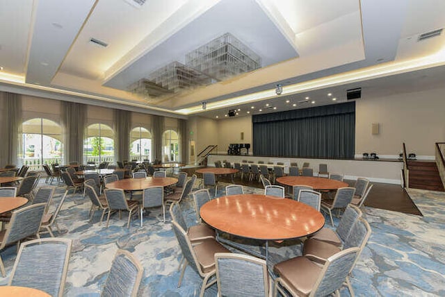 dining room with a tray ceiling, carpet floors, and visible vents