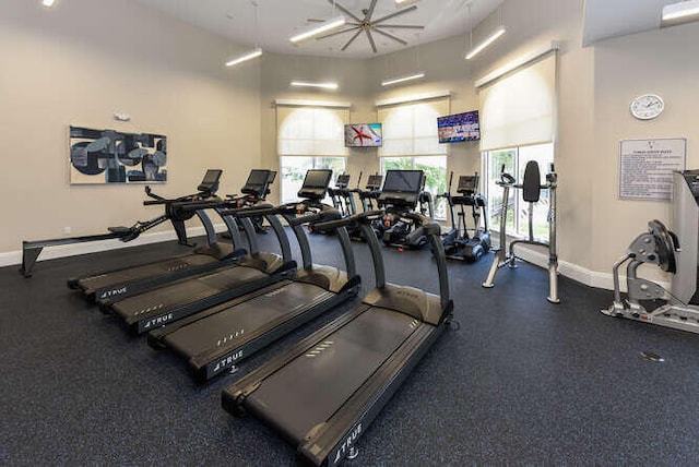 gym featuring a high ceiling and baseboards