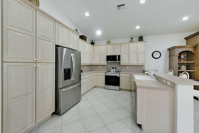 kitchen featuring a peninsula, light countertops, a sink, and appliances with stainless steel finishes