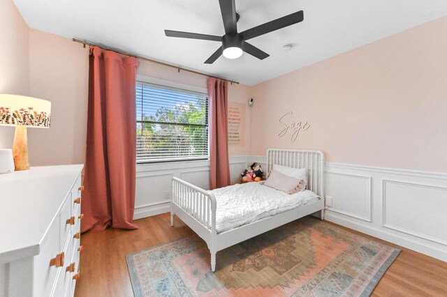 6214 Garrett St, Jupiter, FL 33458 - bedroom featuring light wood-type flooring, ceiling fan, a wainscoted wall, and a decorative wall