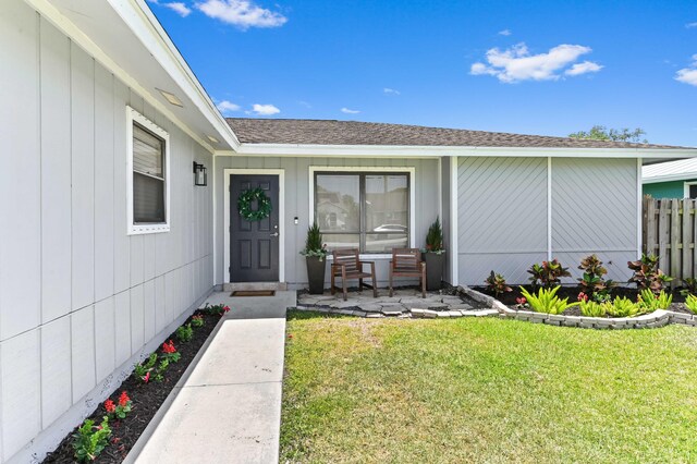 6214 Garrett St, Jupiter, FL 33458 - view of exterior entry featuring roof with shingles, fence, and a yard