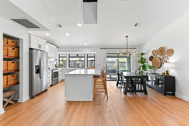 6214 Garrett St, Jupiter, FL 33458 - kitchen featuring a breakfast bar, light wood-style floors, light countertops, stainless steel appliances, and visible vents