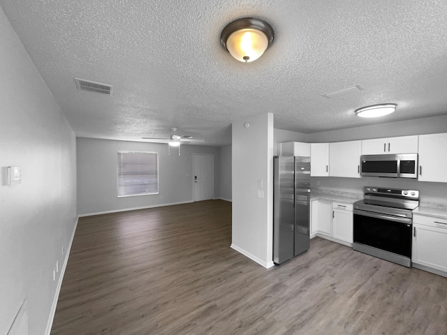 1541 SW Curry St, Port Saint Lucie, FL 34983 - kitchen featuring appliances with stainless steel finishes, open floor plan, light wood-style flooring, white cabinetry, and a textured ceiling