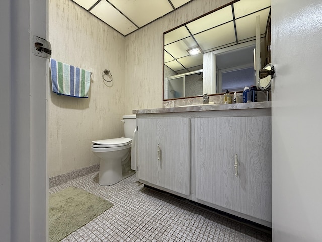 bathroom featuring toilet, vanity, a shower with shower door, baseboards, and tile patterned flooring