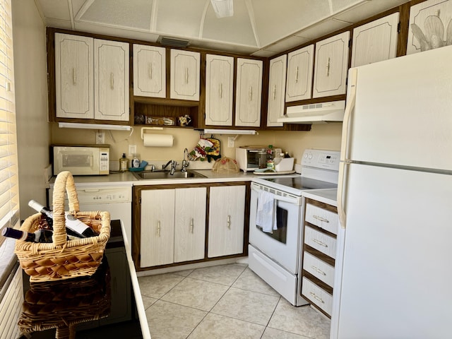 kitchen featuring white appliances, under cabinet range hood, a sink, light countertops, and light tile patterned floors