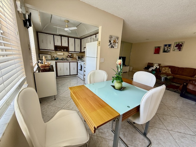 dining space with light tile patterned floors, a ceiling fan, and a textured ceiling
