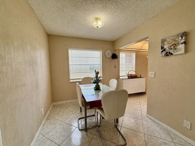 dining room featuring light tile patterned floors, a textured ceiling, and baseboards